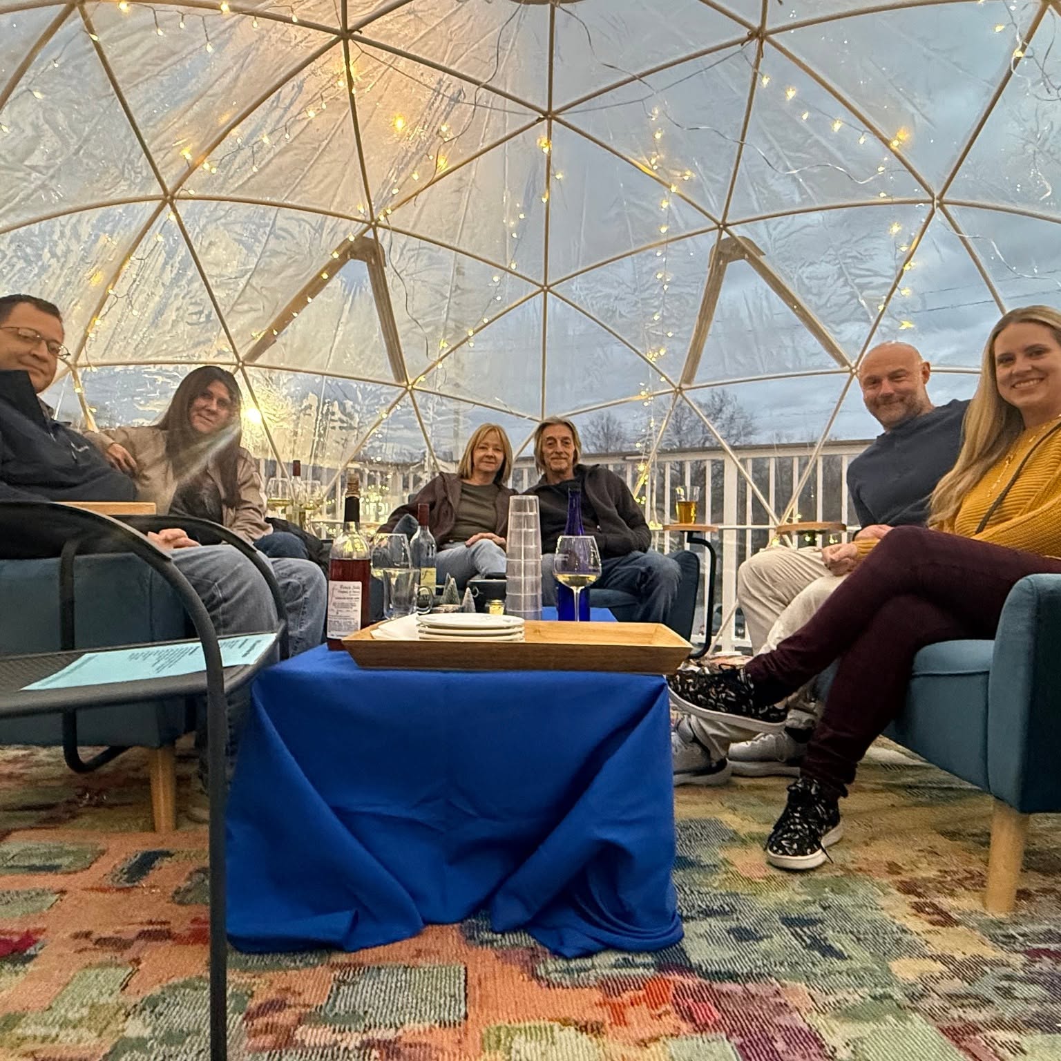 A small group of friends relaxing together on blue sofas inside an NYX igloo.