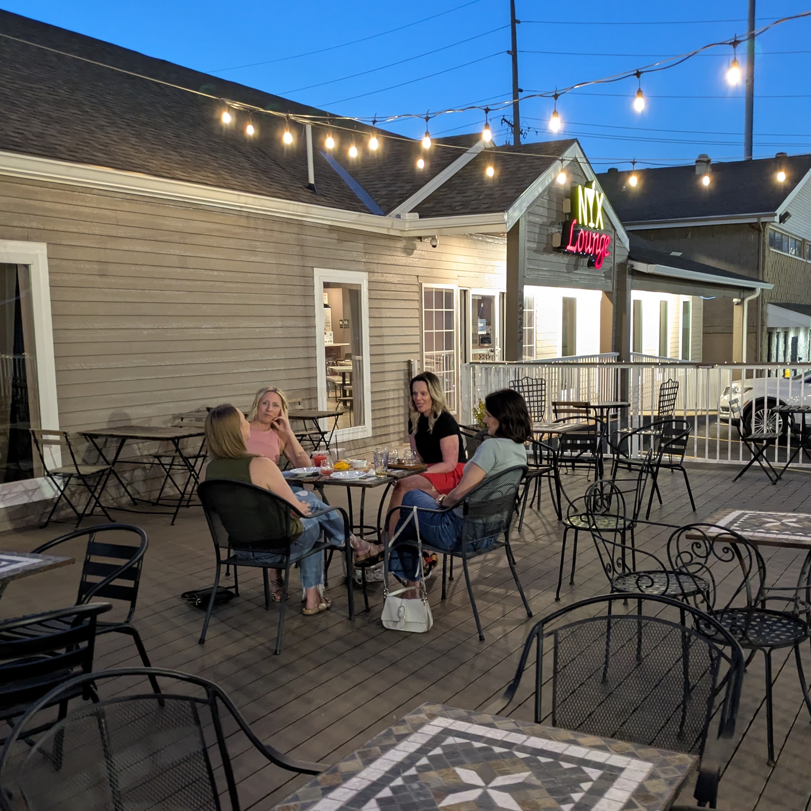Guests gathered on the deck at NYX Spirits and Lounge in Gladstone, Missouri, with string lights and the NYX Lounge sign visible.