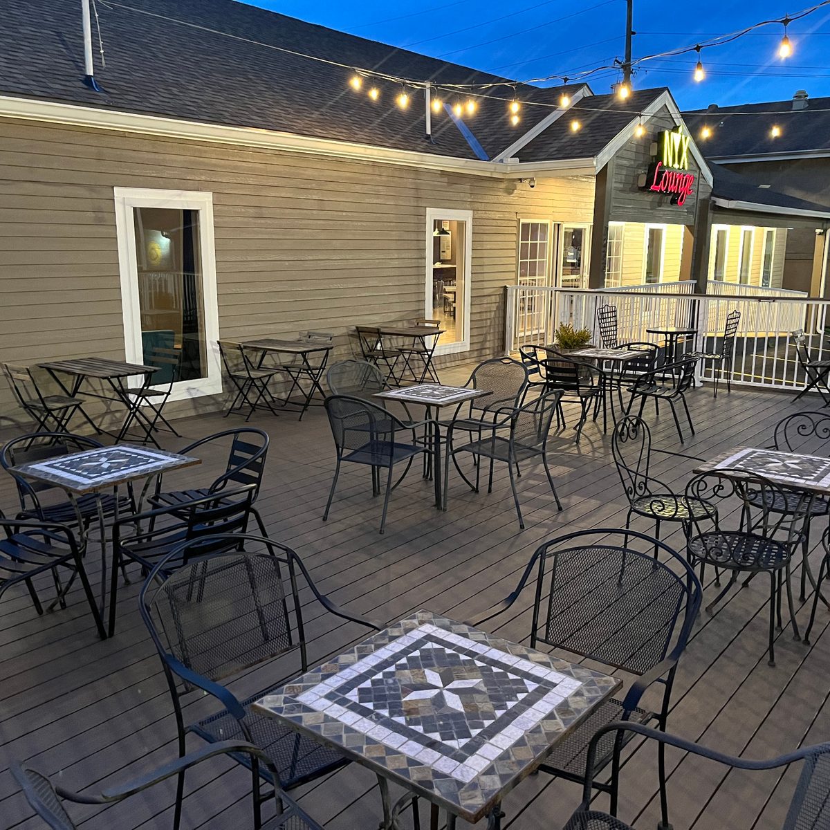 Seasonal deck seating at NYX Spirits & Lounge with string lights and outdoor tables.