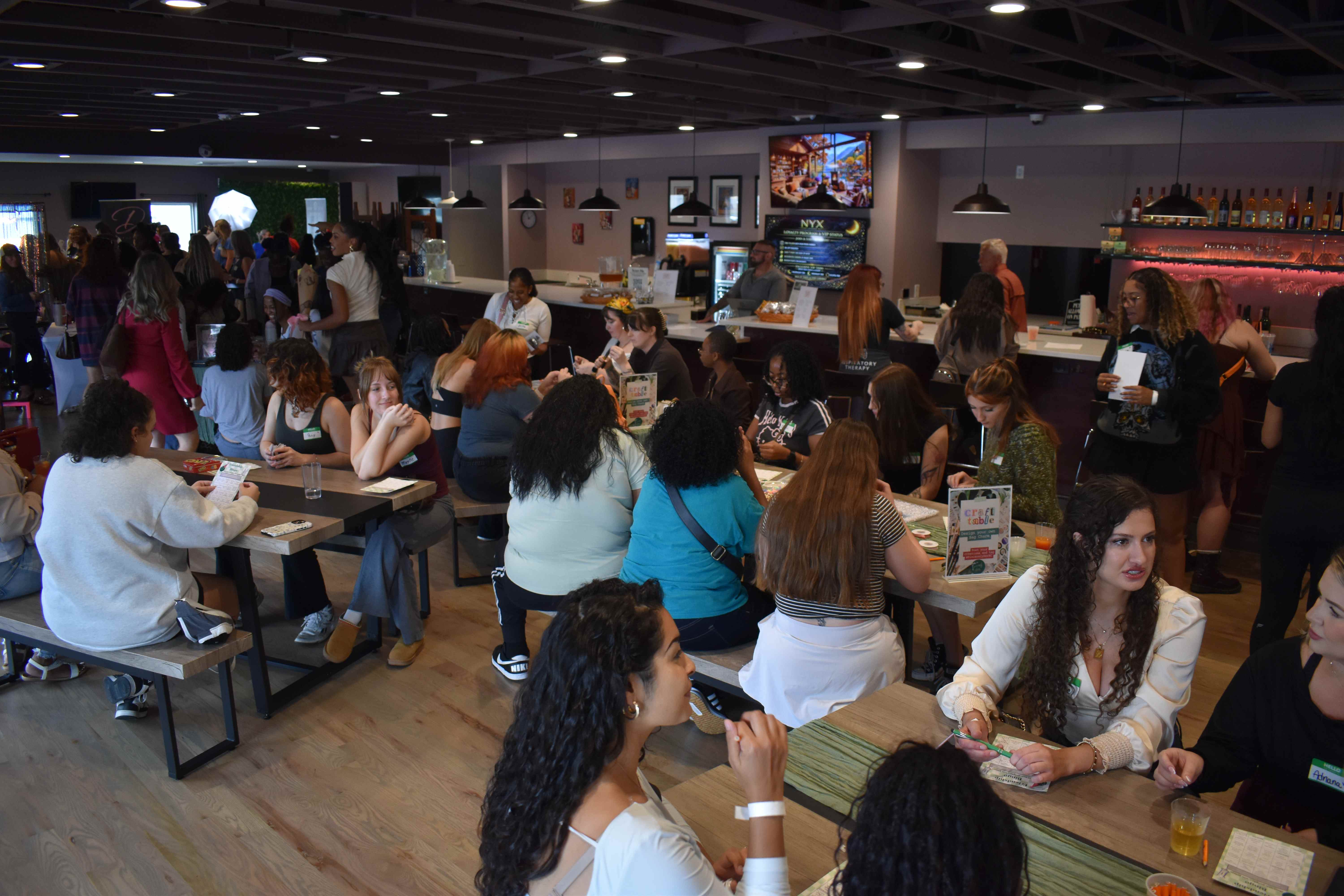 Guests seated around tables in the NYX lounge, with the bar and room in view.